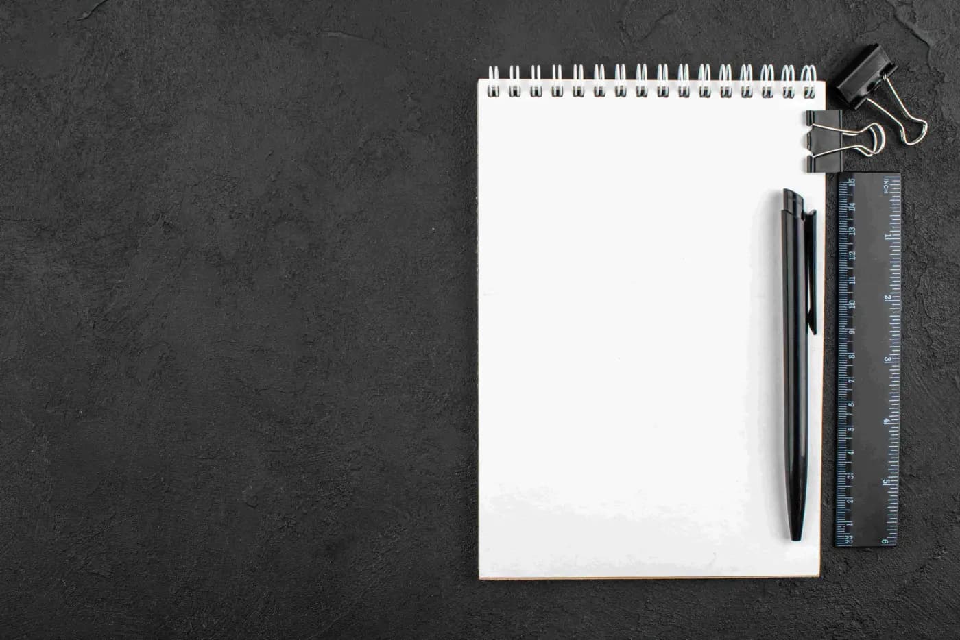 Etap odkrywania celu – biały notes z długopisem na czarnym tle, gotowy do zapisania pomysłów na stronę
